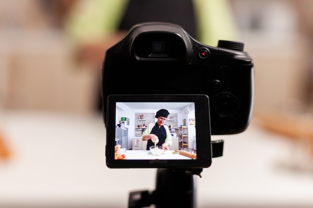 Woman communicating with subscribers through video camera while kneading doug