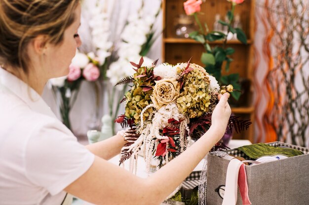 Woman composing creative bouquet in vase