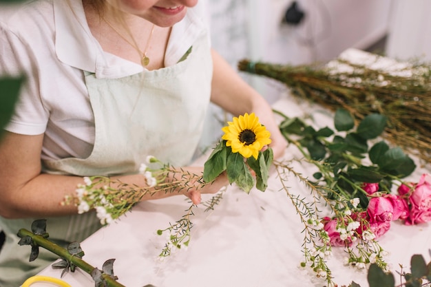 Woman composing flowers together in bouquet