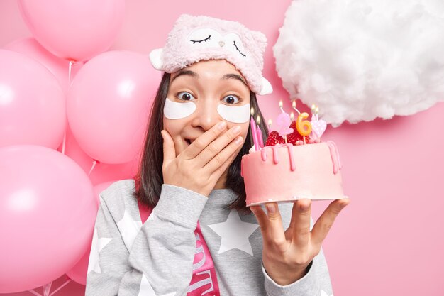 woman cons mouth giggles happily applies patches under eyes to look young and beautiful holds tasty cake celebrates birthday