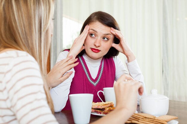 woman consoling the depressed girl at table