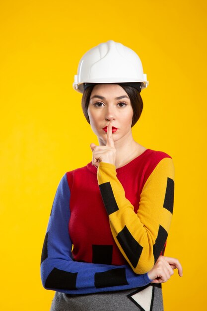 Woman in construction helmet shows to be silent