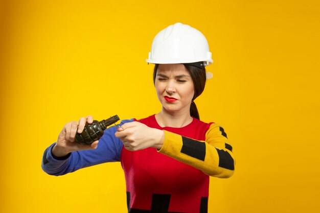 Женщина в строительной каске с копией ручной гранаты