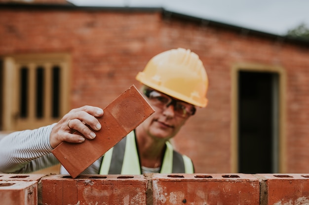 Woman contactor laying bricks outside the home