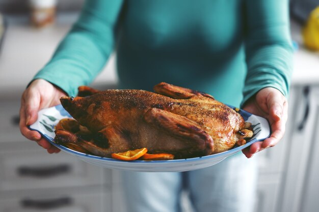 アヒルを野菜で調理し、オーブンから出す女性。ライフスタイル。クリスマスや感謝祭のコンセプト。