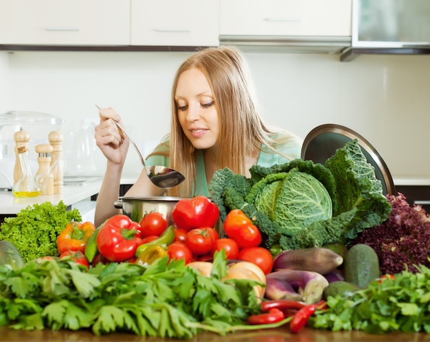 Женщина приготовления пищи с кучей сырых овощей