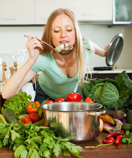 Женщина приготовления пищи с ковшом из овощей