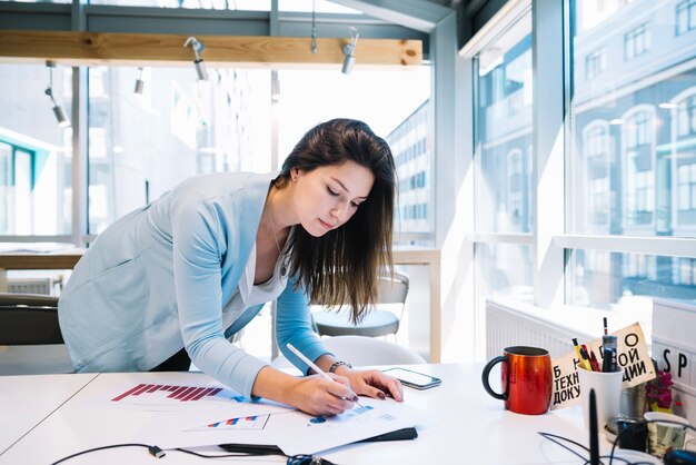 Woman correcting charts near window