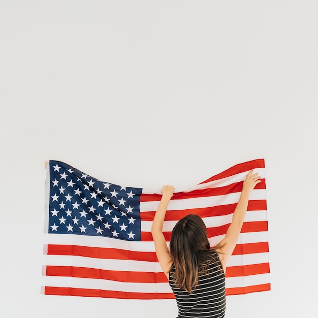 Woman correcting flag of America on wall