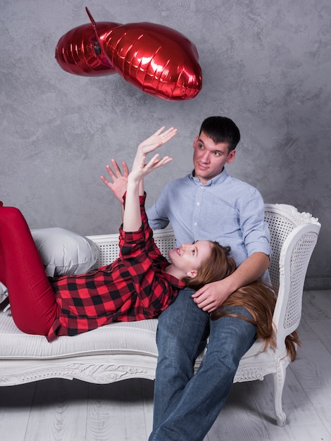 Woman on couch throwing up heart balloons 