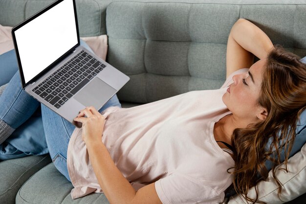 ノートパソコンとソファの上の女性