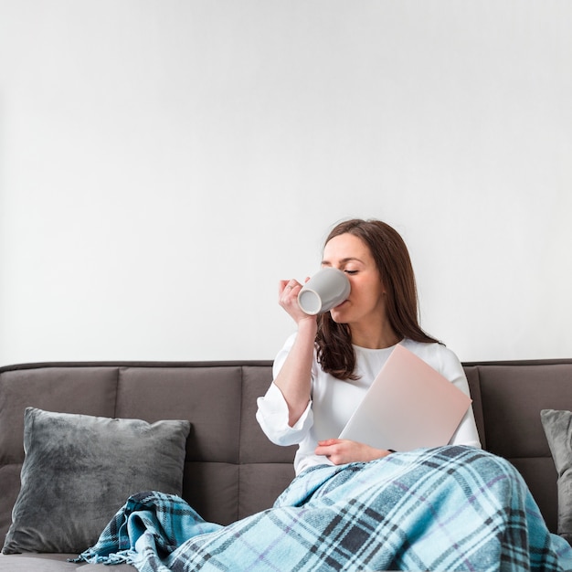 Woman on the couch with mug and copy space