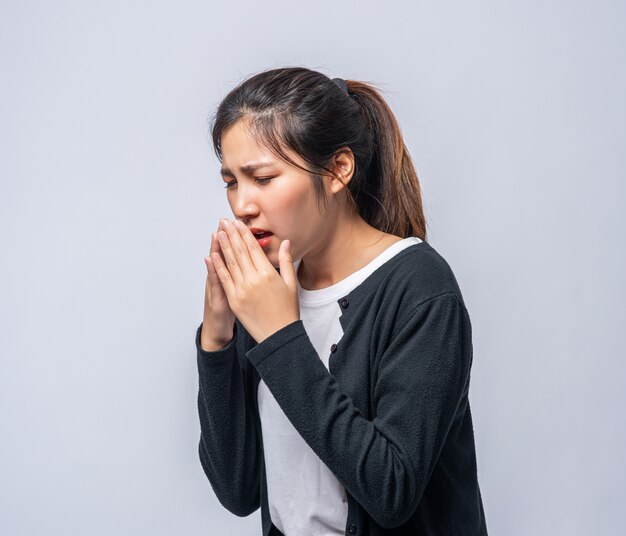 A woman coughing and covering her mouth with her hand