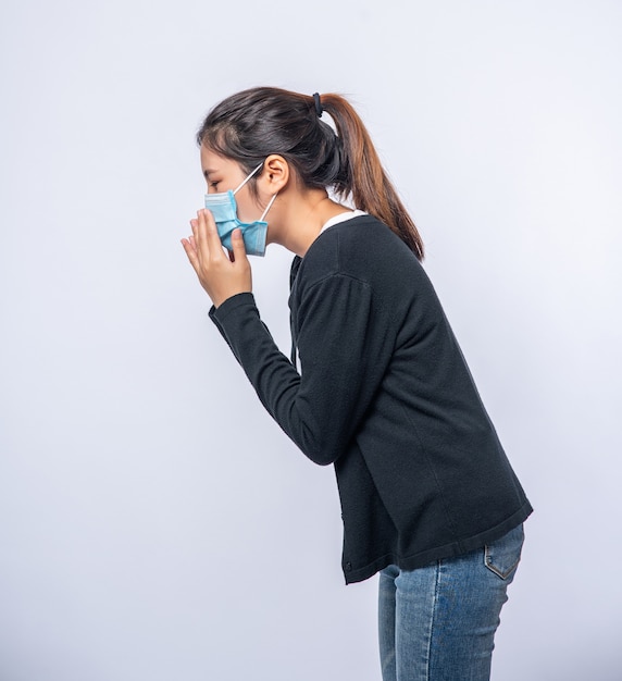 Free photo a woman coughing and covering her mouth with her hand