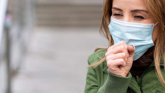 Woman coughing in public space but wearing a mask