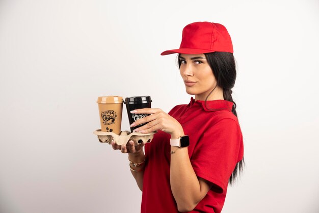 Woman courier holding coffee cups on white background. High quality photo