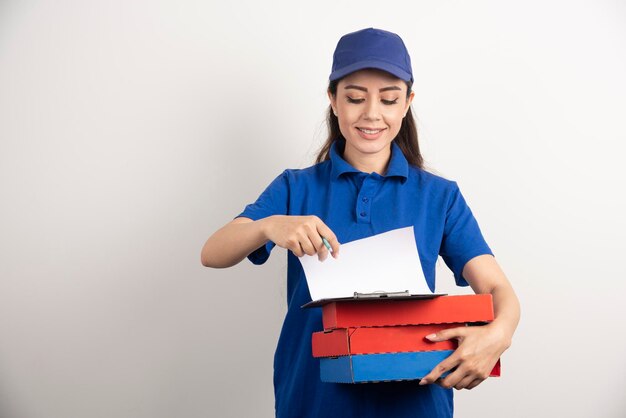 Женщина-курьер смотрит на картон пиццы и буфера обмена