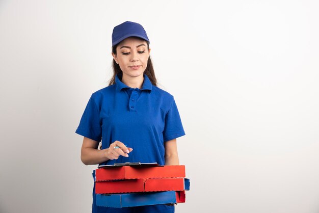 Woman courier looking on cardboard of pizza and clipboard