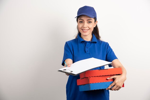 Woman courier with cardboard of pizza giving clipboard . High quality photo