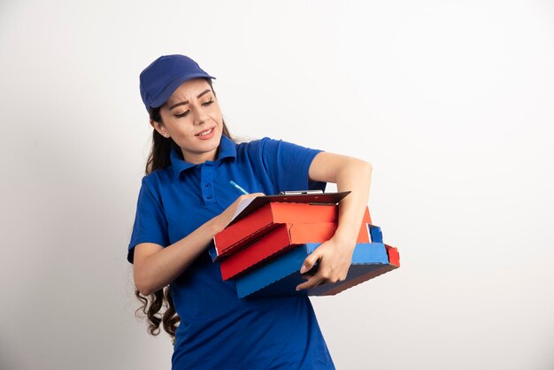 Женщина-курьер пишет в буфере обмена и держит картоны с пиццей