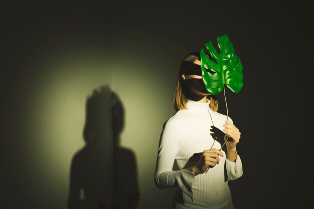 Женщина закрыла лицо большим зеленым листом