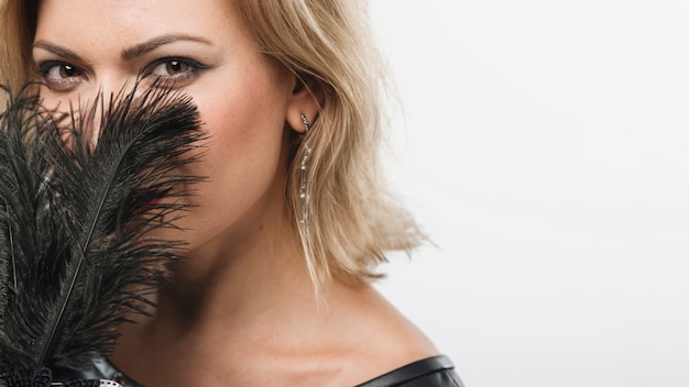 Free photo woman covering face with feathers of mask