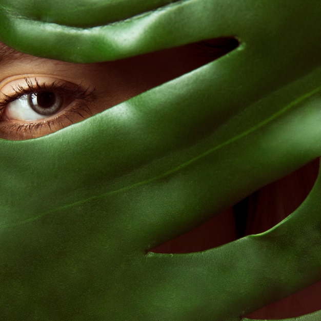 Free photo woman covering face with green leaf