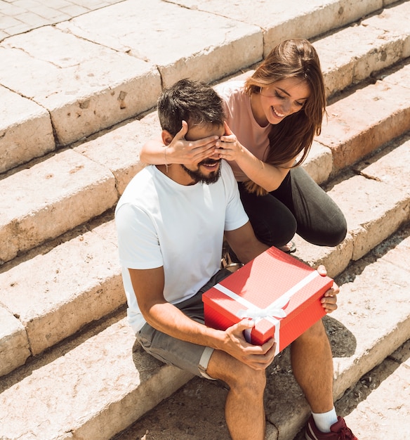 Foto gratuita donna che copre gli occhi del suo ragazzo e lo sorprende con un regalo