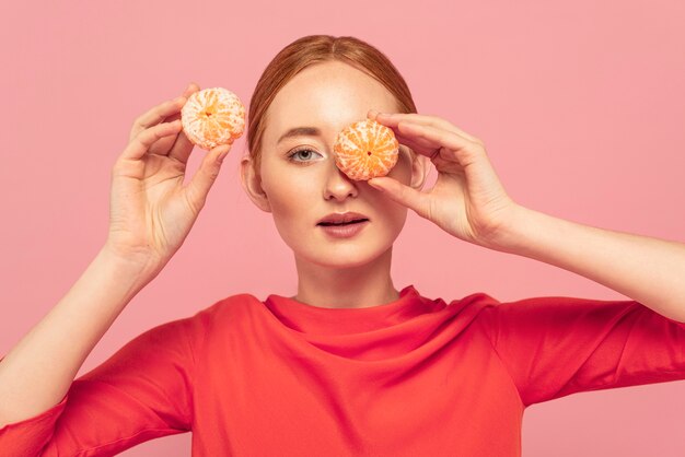 Woman covering her eyes with oranges