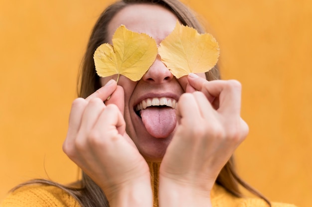 Woman covering her eyes with yellow leaves