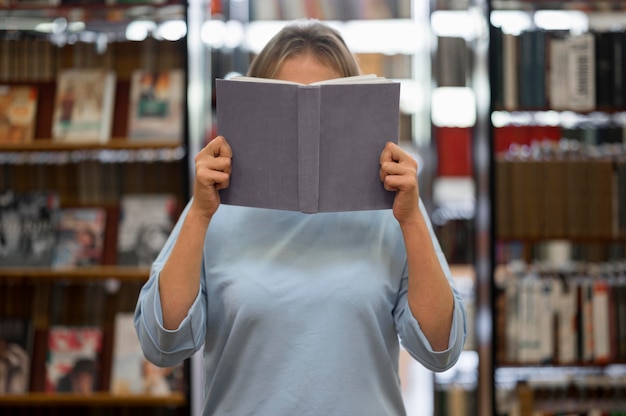 Foto gratuita donna che copre il viso con il libro