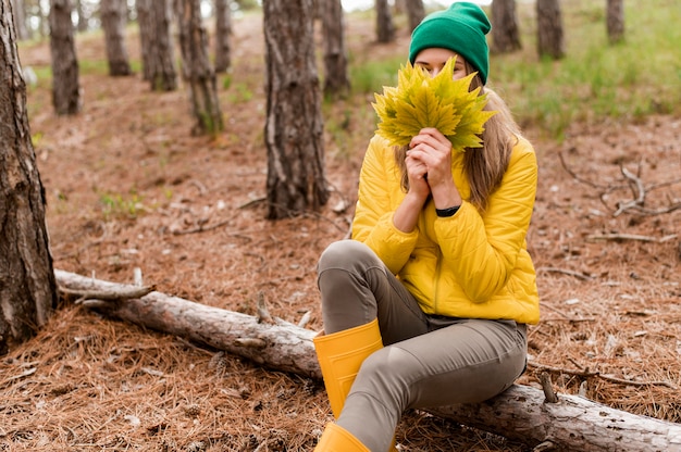 Woman covering her face with a bunch of autumn leaves