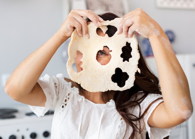 Woman covering her face with cookies dough