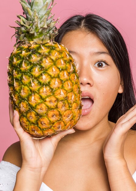 Woman covering her face with full size pineapple