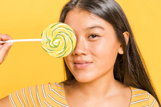 Woman covering her face with lollipop and looking at camera