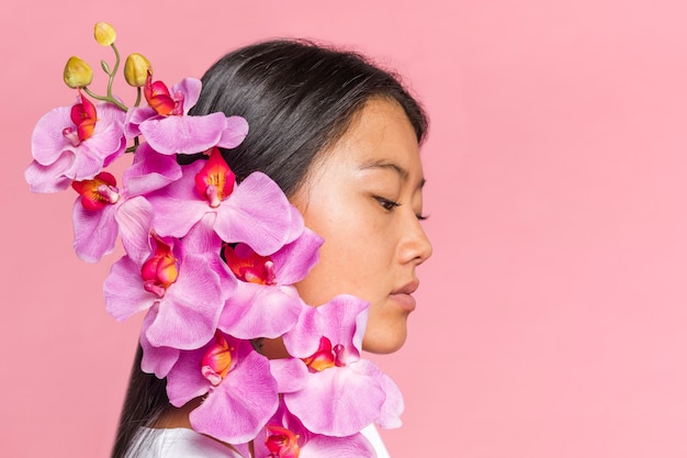 Foto gratuita donna che copre il viso con petali di orchidea lateralmente