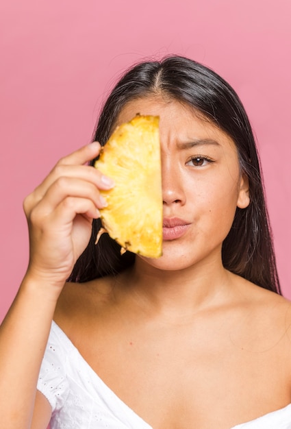 Woman covering her face with sliced pineapple