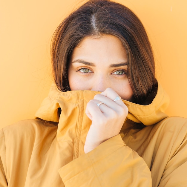 Free photo woman covering her mouth with jacket looking at camera