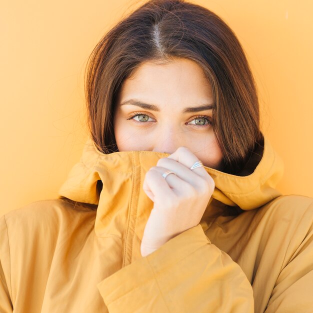 woman covering her mouth with jacket looking at camera