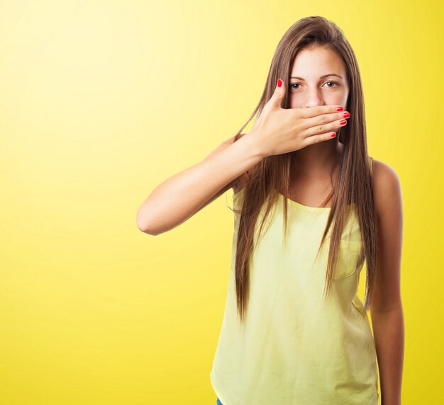 Woman covering her mouth in a yellow background