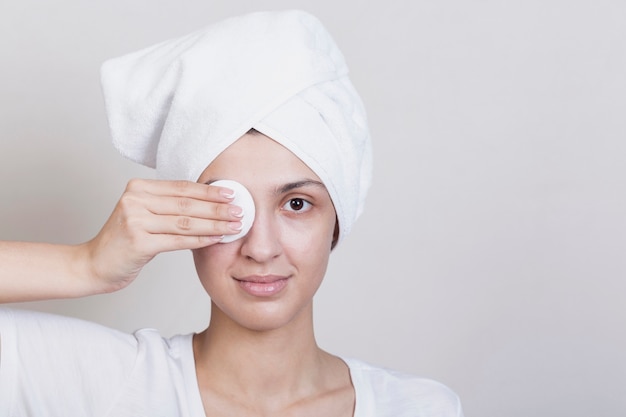 Free photo woman covering one eye with makeup disc