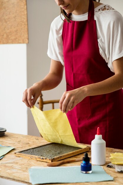 Woman covering paper pulp with yellow cloth