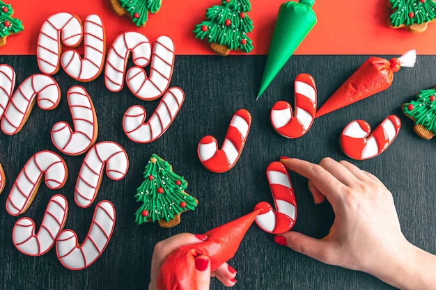 Free photo a woman covers with icing christmas gingerbread in the form of a candy