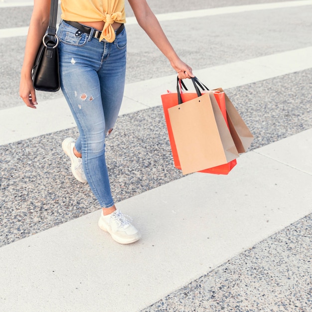 Free photo woman crossing the street with shopping bags