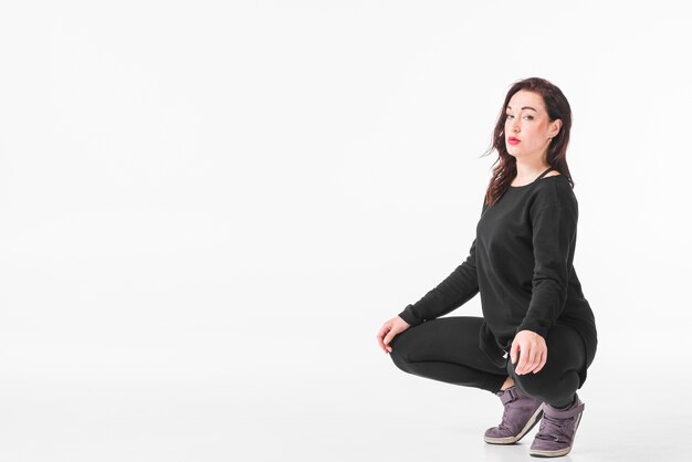 Woman crouching against blank white backdrop