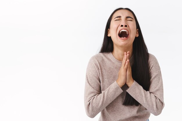 woman crying her heart out begging for mercy or apology, telling she sorry, holding hands in pray, having mental breakdown, dont know what do, supplicating