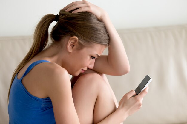 Woman crying while reading  message on cellphone