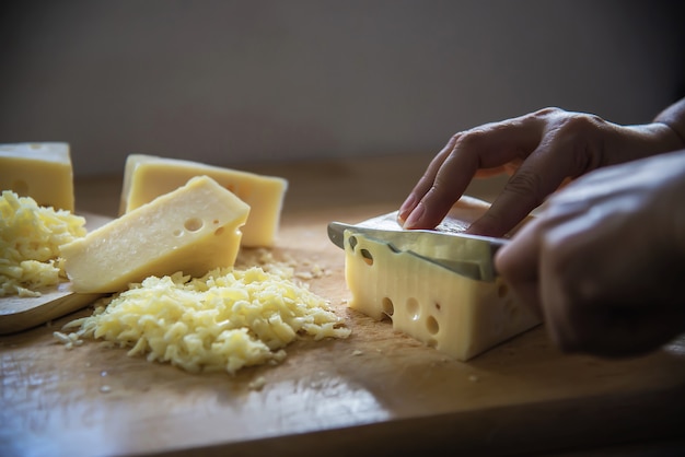 여자는 부엌에서 칼을 사용하여 요리사 요리 슬라이스 치즈-치즈 개념 음식을 만드는 사람들