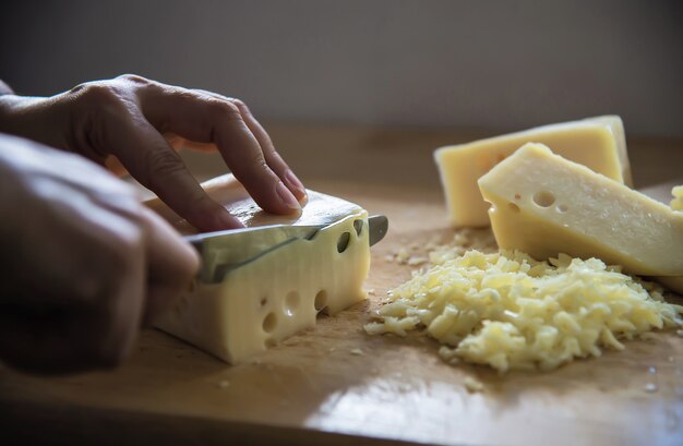 Woman cut slice cheese for cook using knife in the kitchen - people making food with cheese concept