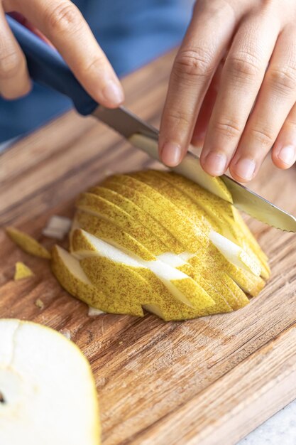 A woman cuts a pear into small pieces closeup